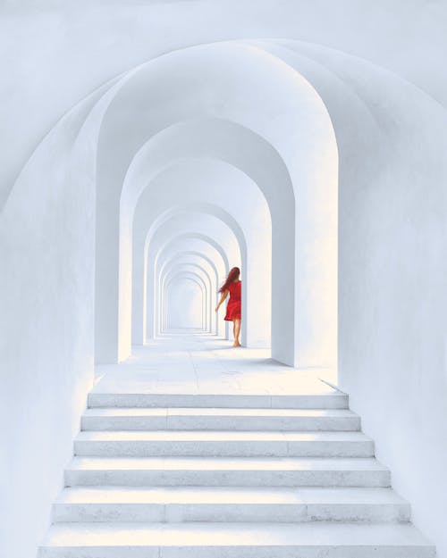 Woman in Red Dress Standing in White Arch Building