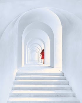 A woman in a red dress walks through a series of white arches, creating a stunning contrast and leading lines.