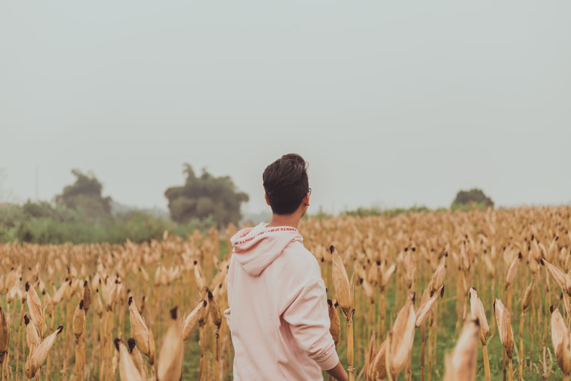 Man in White Hoodie Standing on White Grass Field