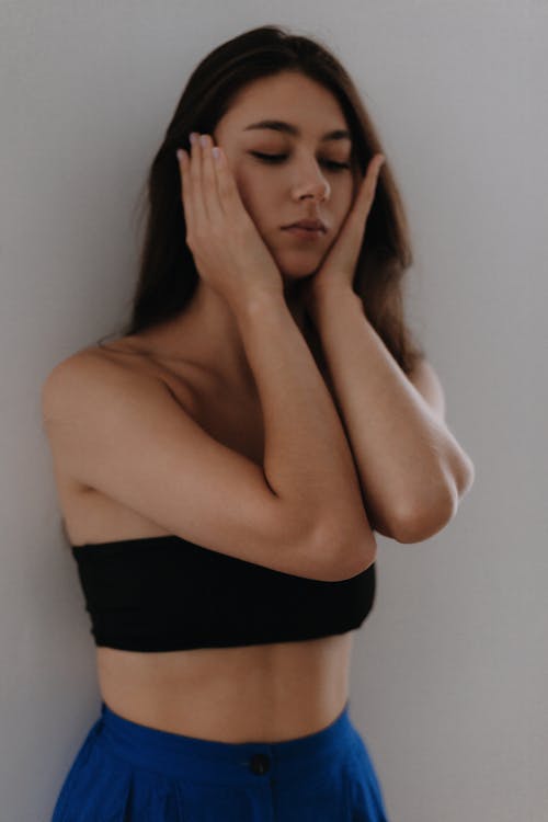 Young Woman in Black Bandeau Top Covering her Ears with Hands