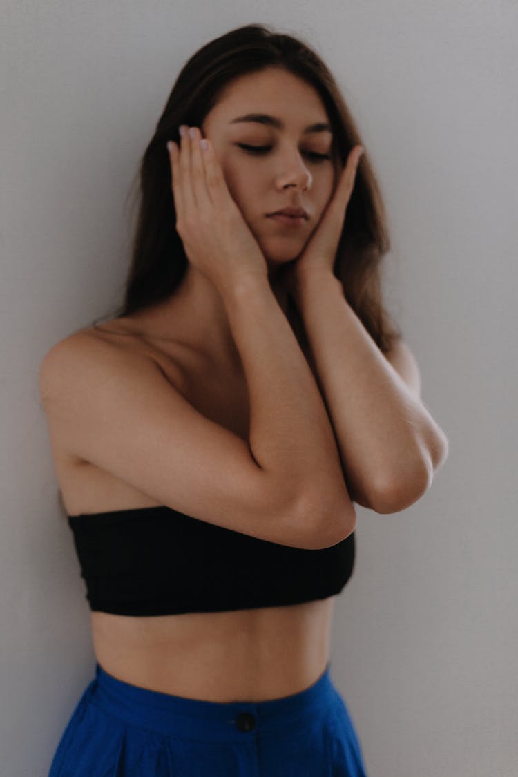 Young Woman In Black Bandeau Top Covering Her Ears With Hands