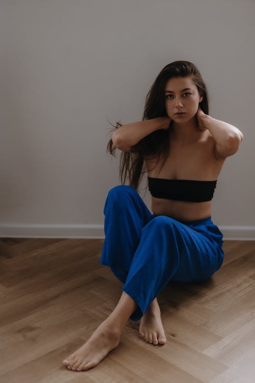 Woman in Blue Pants and Black Bandeau Top Posing Sitting on the Floor