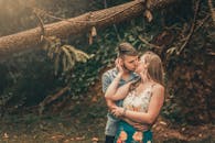 一对情侣在郁郁葱葱的森林中浪漫亲吻，为景色增添了一丝自然和亲密感