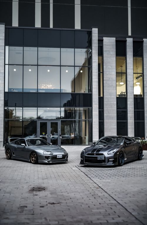 Free Sleek sports cars parked outside a modern glass-fronted showroom. Stock Photo