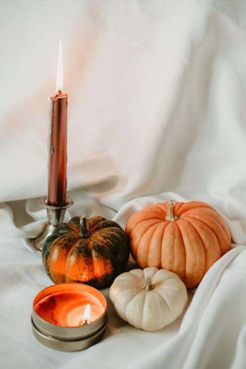 Free Warm autumn ambiance featuring candles and pumpkins on soft fabric backdrop. Stock Photo