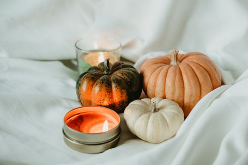 Free Warm and inviting autumn scene featuring pumpkins and lit candles on a white sheet. Stock Photo