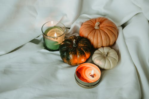 Candles and Pumpkins on a White Sheet 