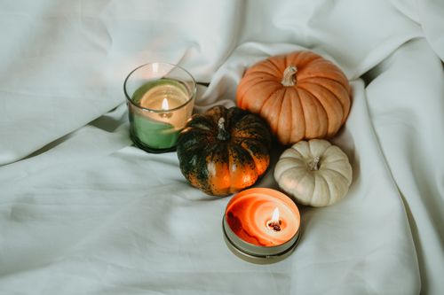 Free Warm autumn scene featuring pumpkins and candles on a soft white backdrop, perfect for seasonal decor. Stock Photo