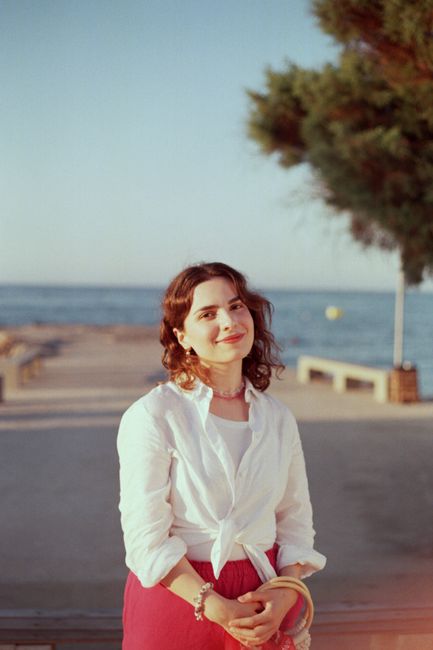 A woman smiling at the beach during sunset, enjoying a summer day by the sea.