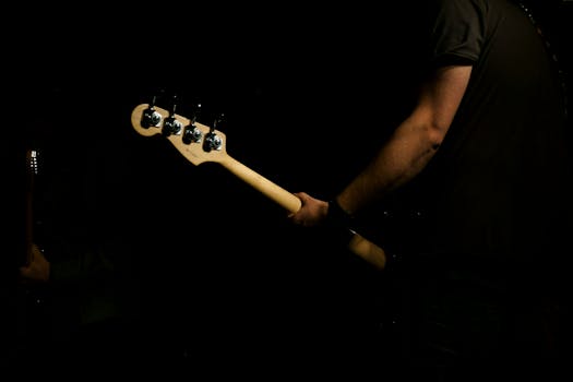 Striking image of a man playing electric guitar against a black background, emphasizing passion and mood.