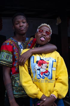 一对时尚的非裔美国年轻人开玩笑地摆出姿势，在城市背景下拥抱充满活力的时尚