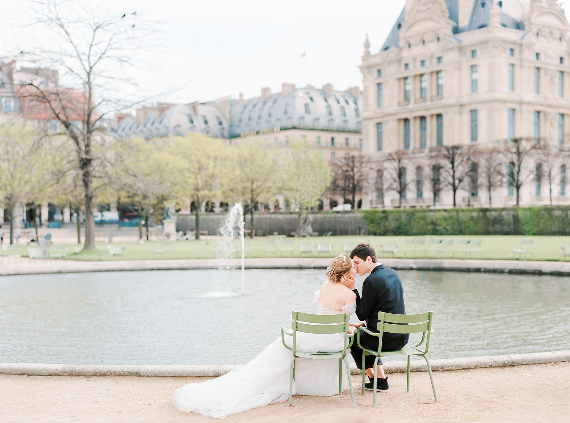 Newlywed couple embraces by a fountain in Paris, capturing a romantic urban scene.