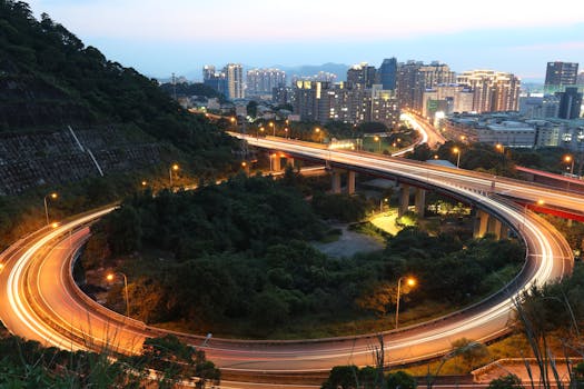 Long exposure of Taipei City overpass with city skyline and light trails at night.