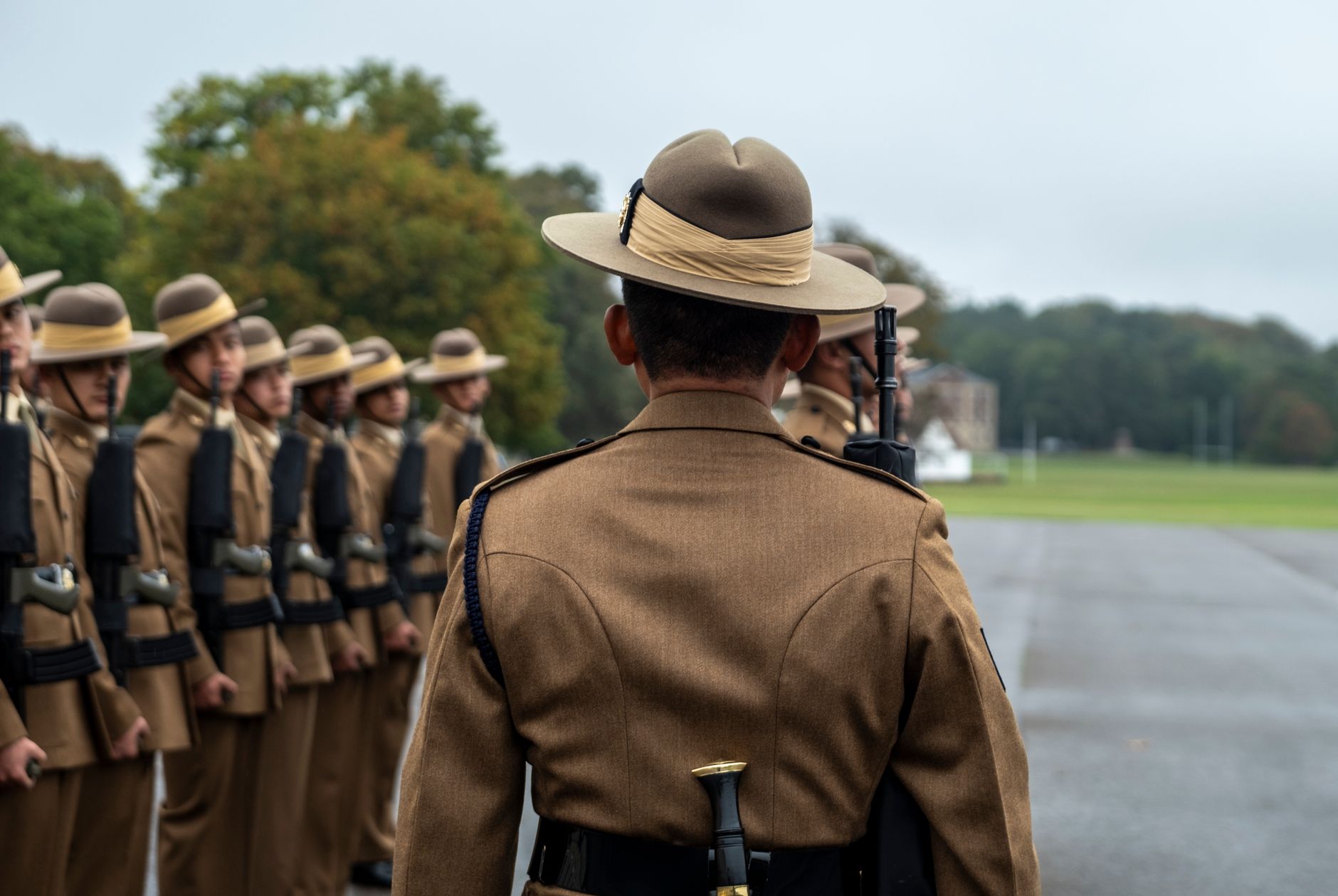 Military personnel standing in formation wearing traditional uniforms outdoors.