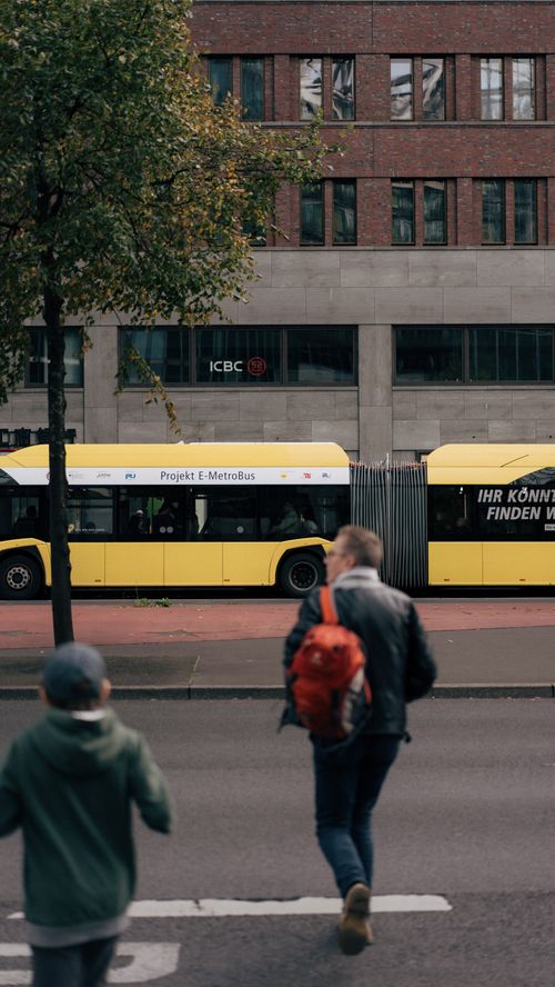Free City street view with yellow bus, pedestrians, and urban architecture. Stock Photo