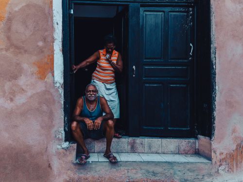 Free A senior couple enjoying a relaxed moment at their home's doorstep, capturing a warm, everyday scene. Stock Photo