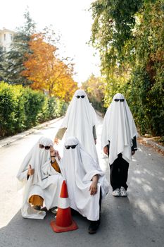 A group of people dressed as ghosts with sunglasses on an autumn street, celebrating Halloween.