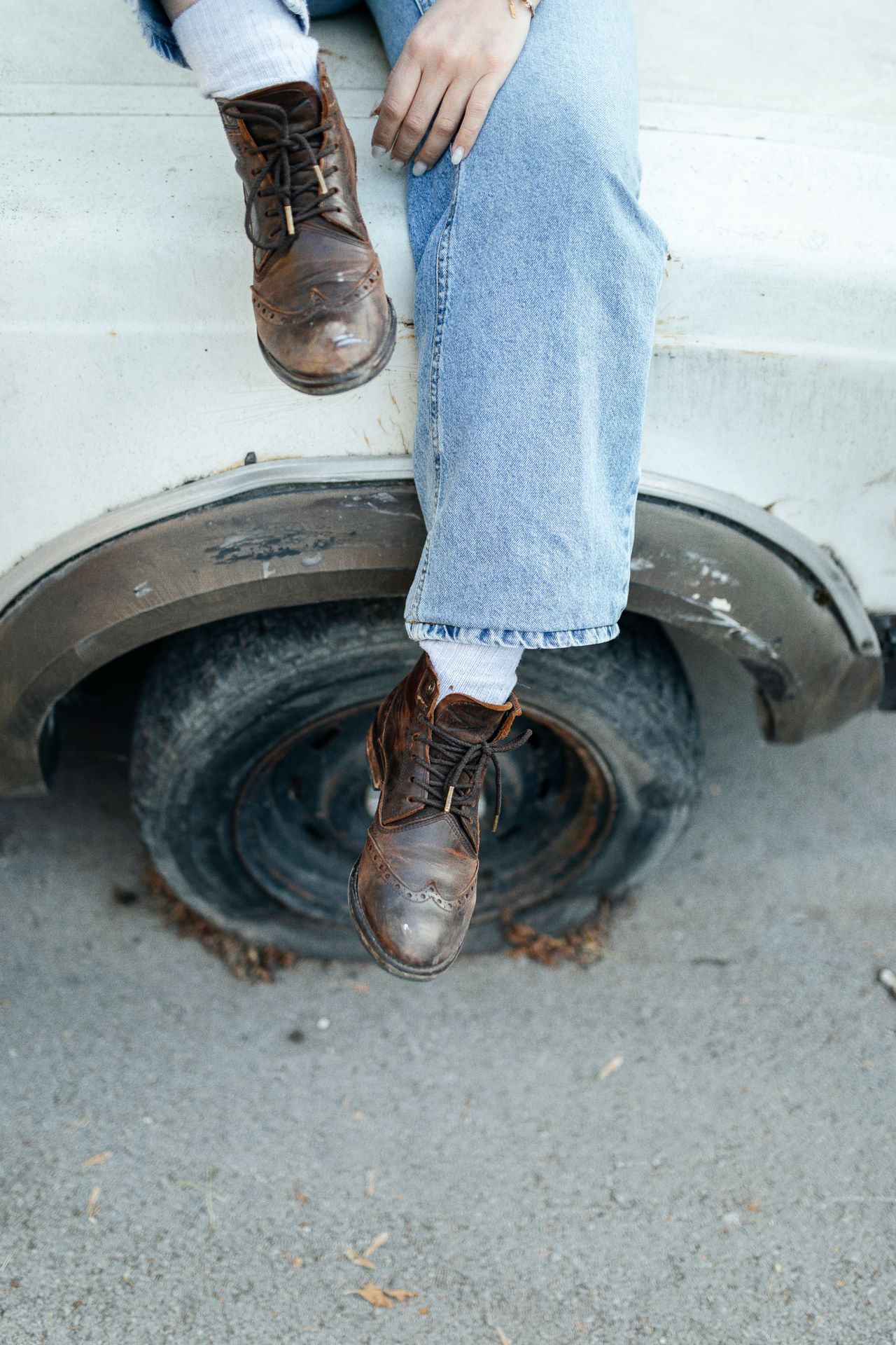 Woman in jeans and brown ankle boots sitting on a truck