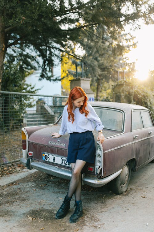 Young Model in a Light Purple Blouse and Navy Blue Mini Skirt Next by an Old Abandoned Car