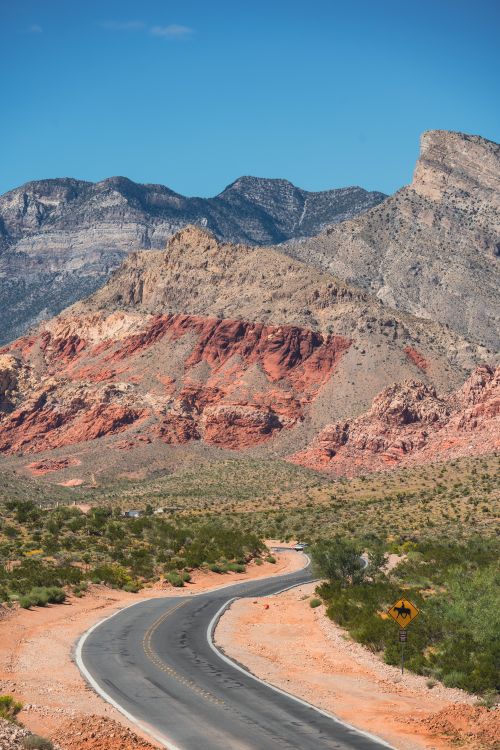 Free Winding road through Red Rock Canyon in Nevada with dramatic rock formations and clear skies. Stock Photo