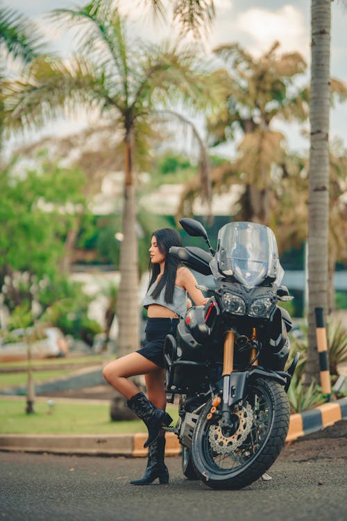 Woman in Black Mini Skirt, Boots, and Gray Crop Top Posing by a Motorcycle