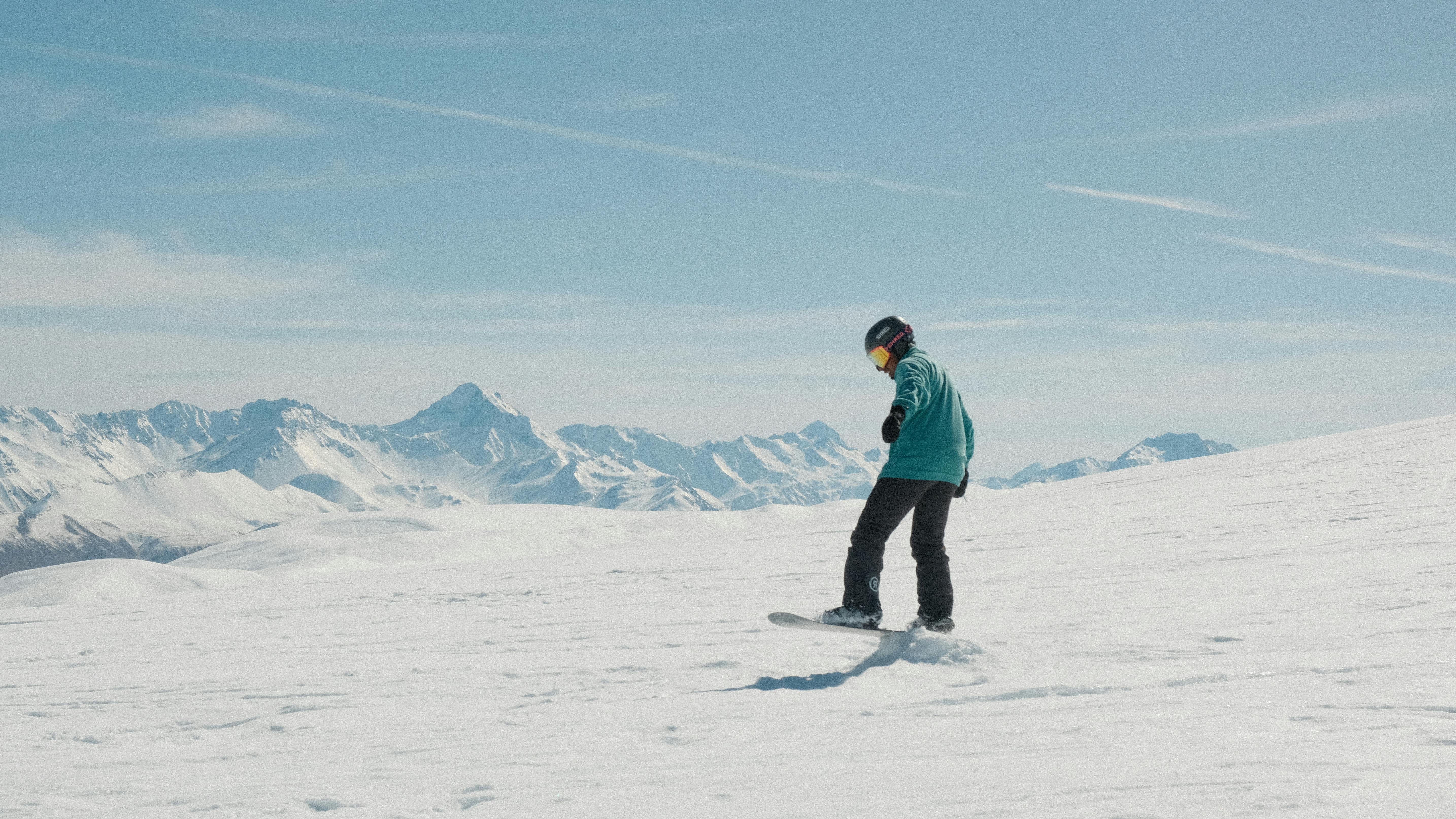 A snowboarder enjoying a sunny winter day on a snow-covered mountain.