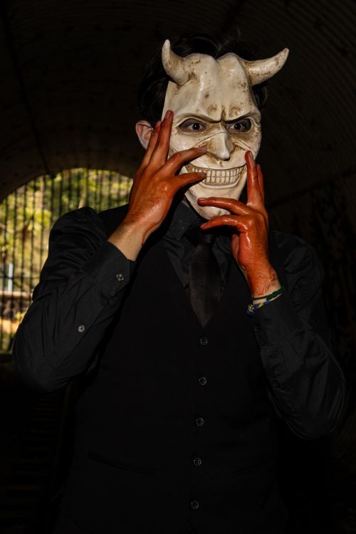 Free A mysterious man in a white devil mask poses elegantly in a dark tunnel in Ciudad de México, CDMX, México. Stock Photo
