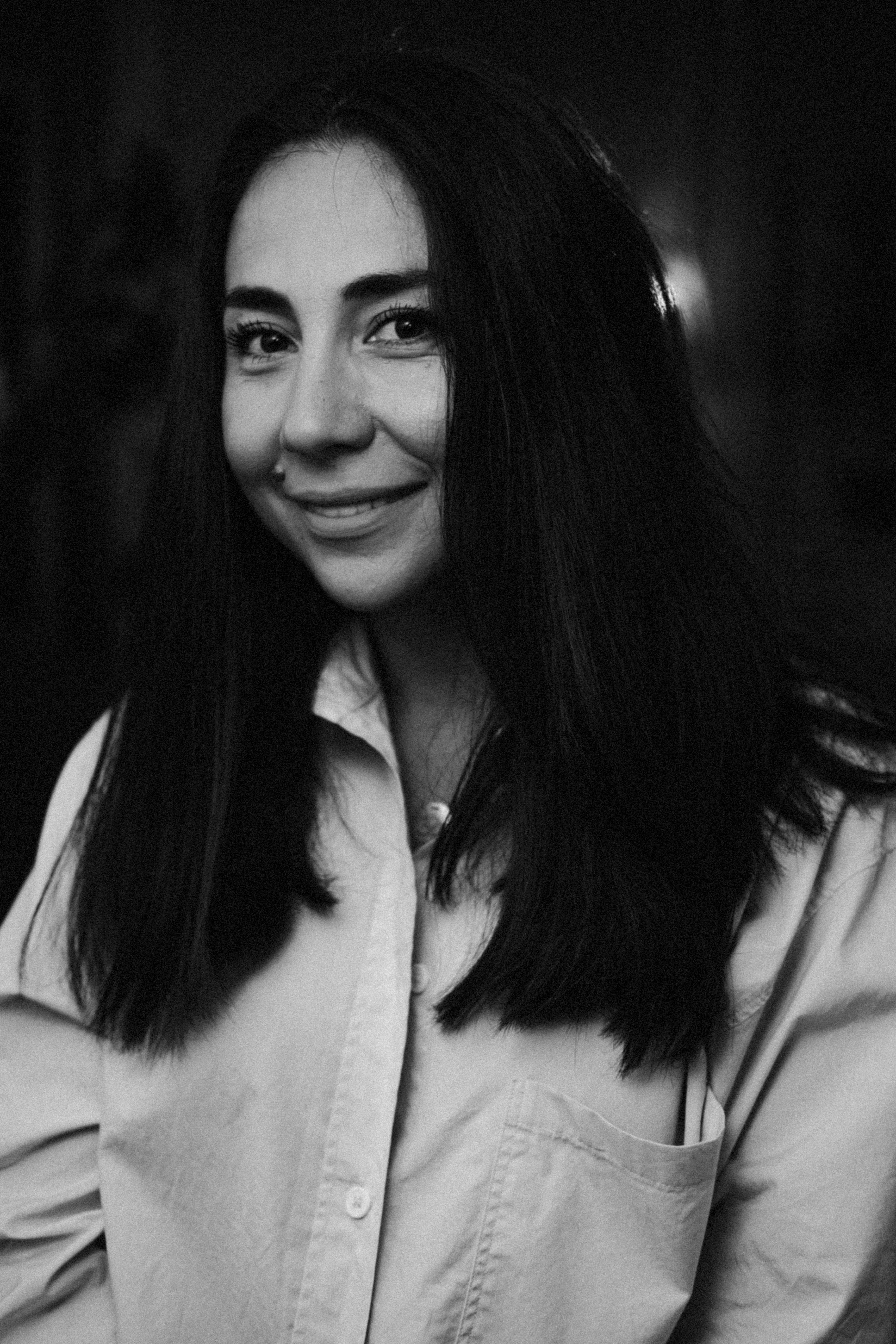 Elegant black and white portrait of a woman smiling softly in a vertical frame.