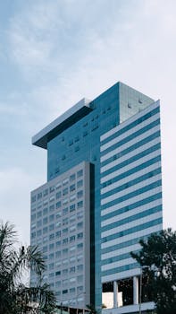 A contemporary glass high-rise office building against a clear sky, showcasing urban architecture.