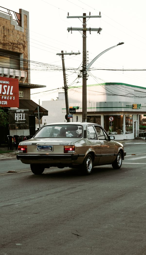 Um carro clássico vintage dirigindo pelas ruas urbanas ao anoitecer, exalando nostalgia e charme urbano.