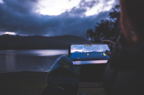 Woman Photographing a Mountain Lake Landscape with a Smart Phone