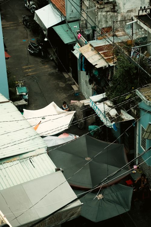 Free High angle view of a narrow urban street with umbrellas and rooftops. Stock Photo