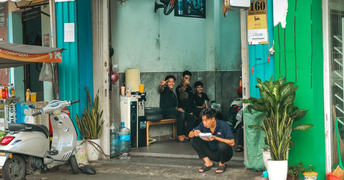 A traveler shaking hands with a Community Watch volunteer in front of a local shop in Ho