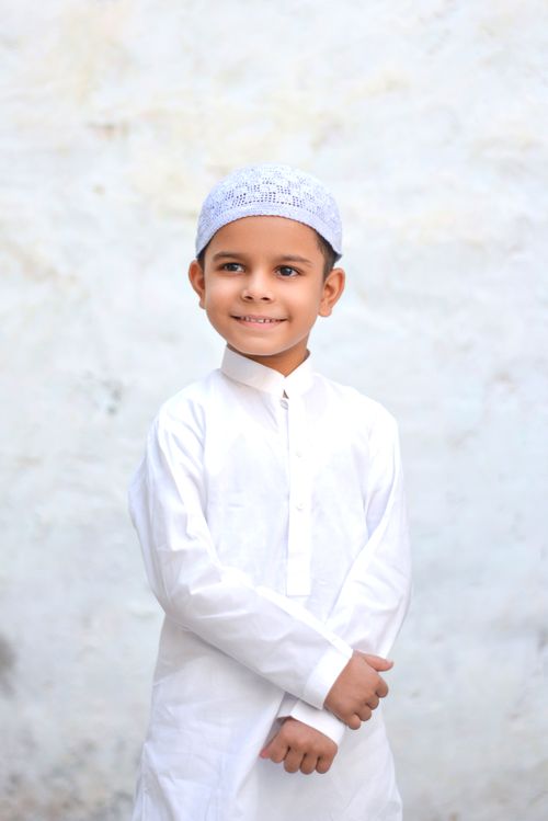 Free Portrait of a smiling boy in traditional clothing against a plain background. Stock Photo
