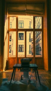 A vintage typewriter sits by a window overlooking historic urban architecture.