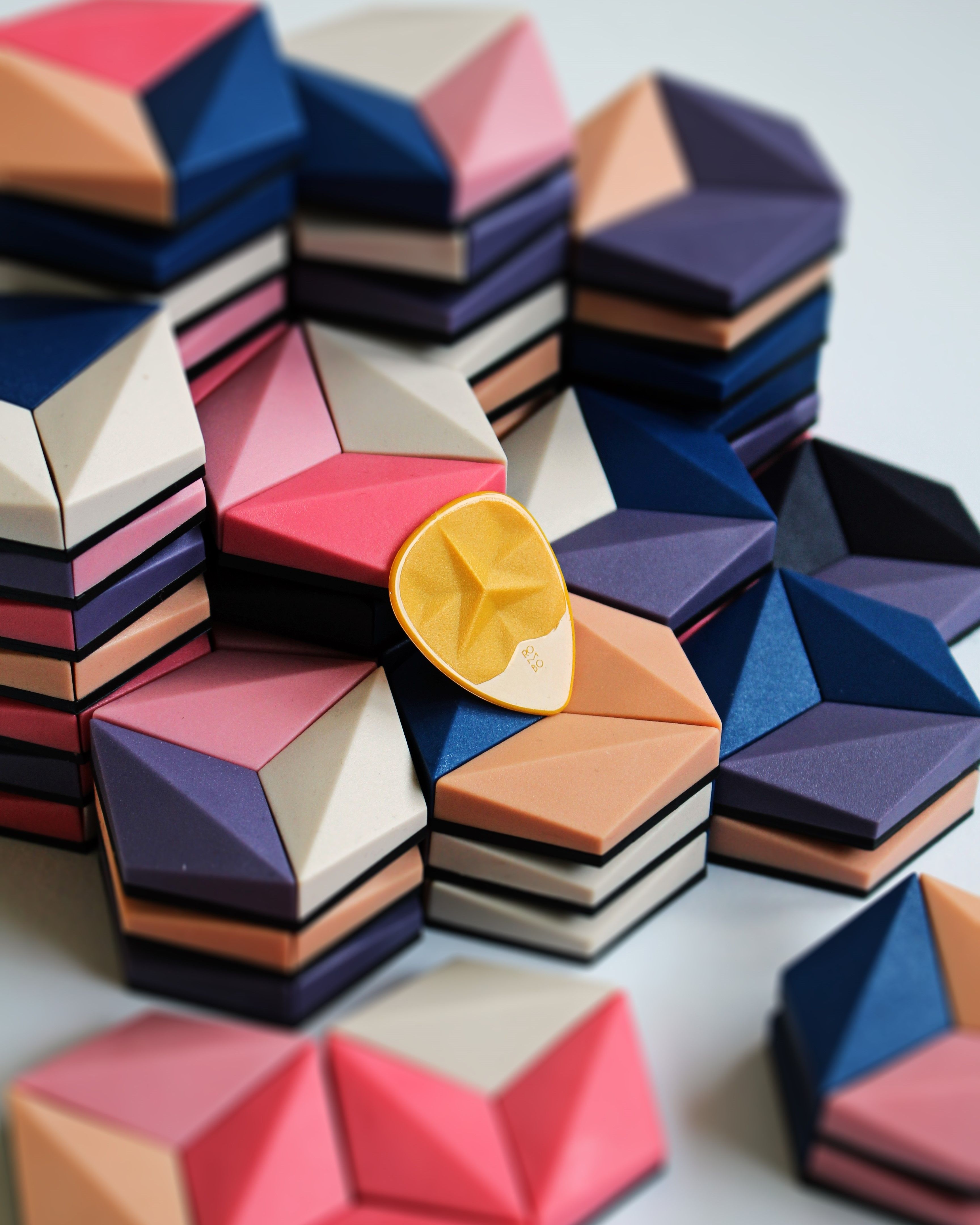 Vibrant geometric guitar picks stacked creatively showing various shades and designs.