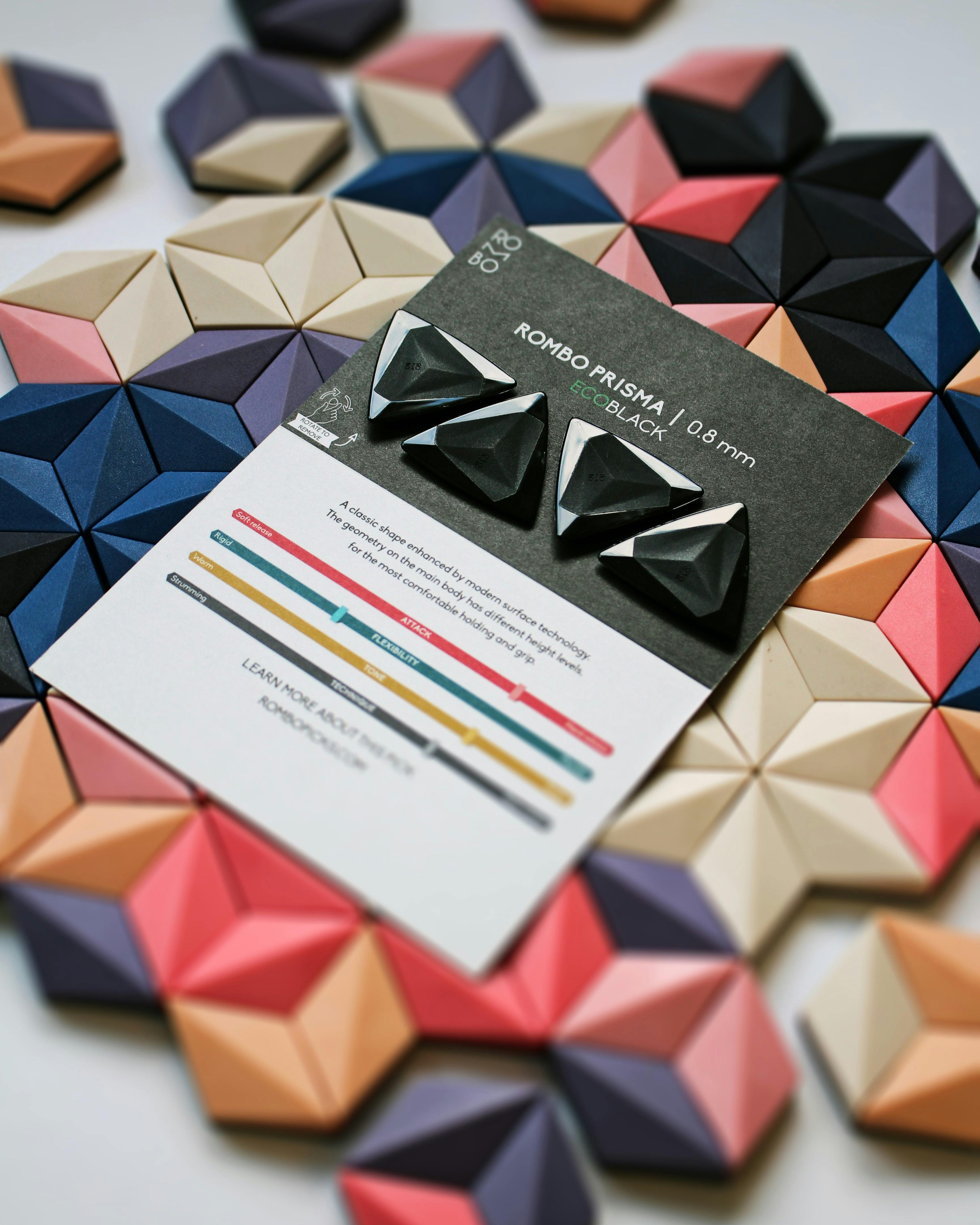Artistic display of black guitar picks with geometric shapes on a colorful background.