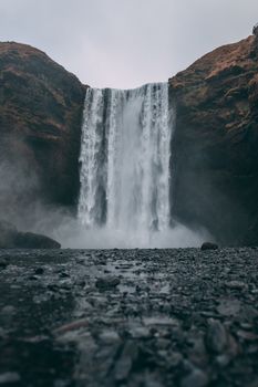 Stunning view of Skógafoss waterfall cascading in a dramatic, misty Icelandic landscape.