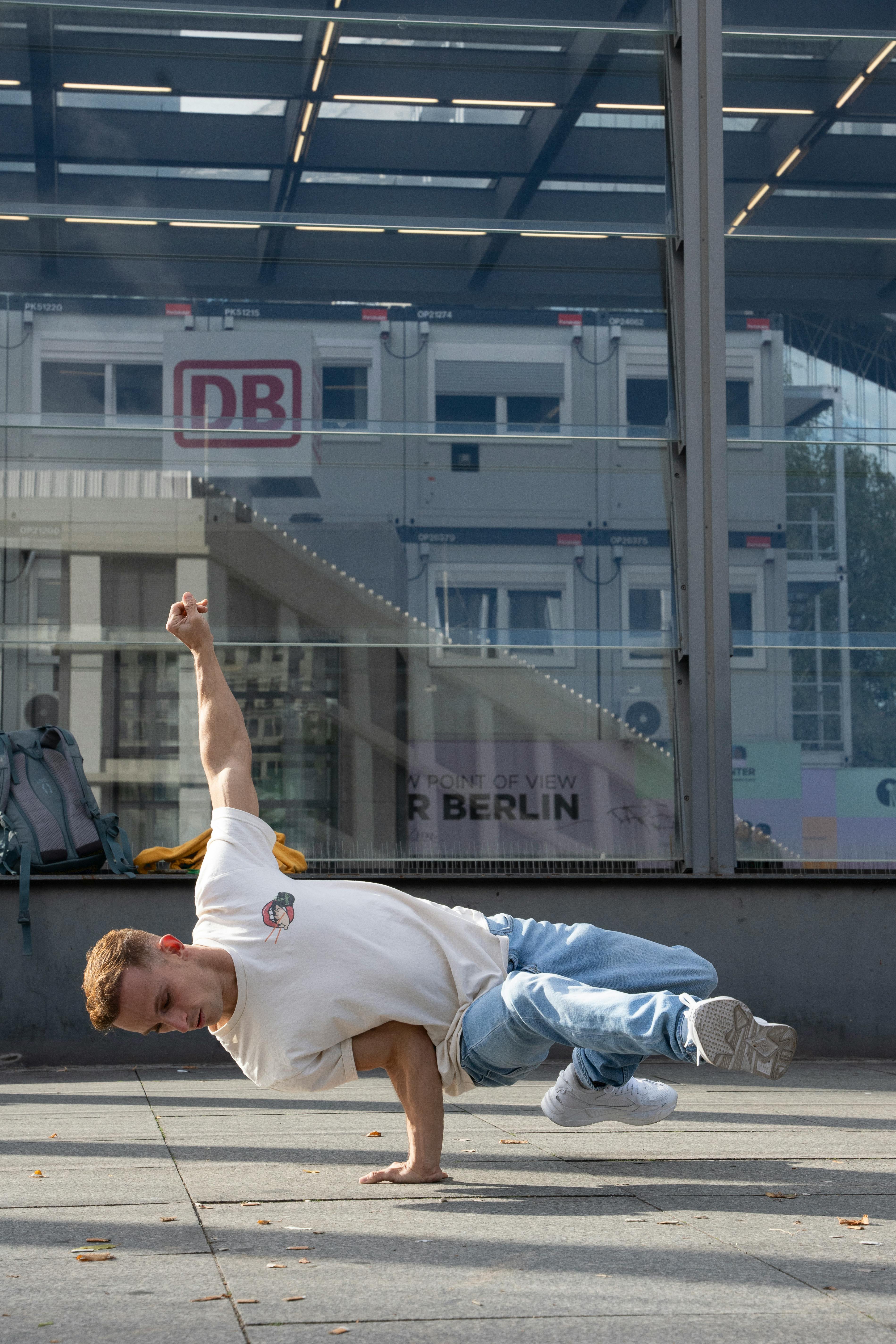 Young man breakdancing on city street in Berlin, showcasing urban dance style.