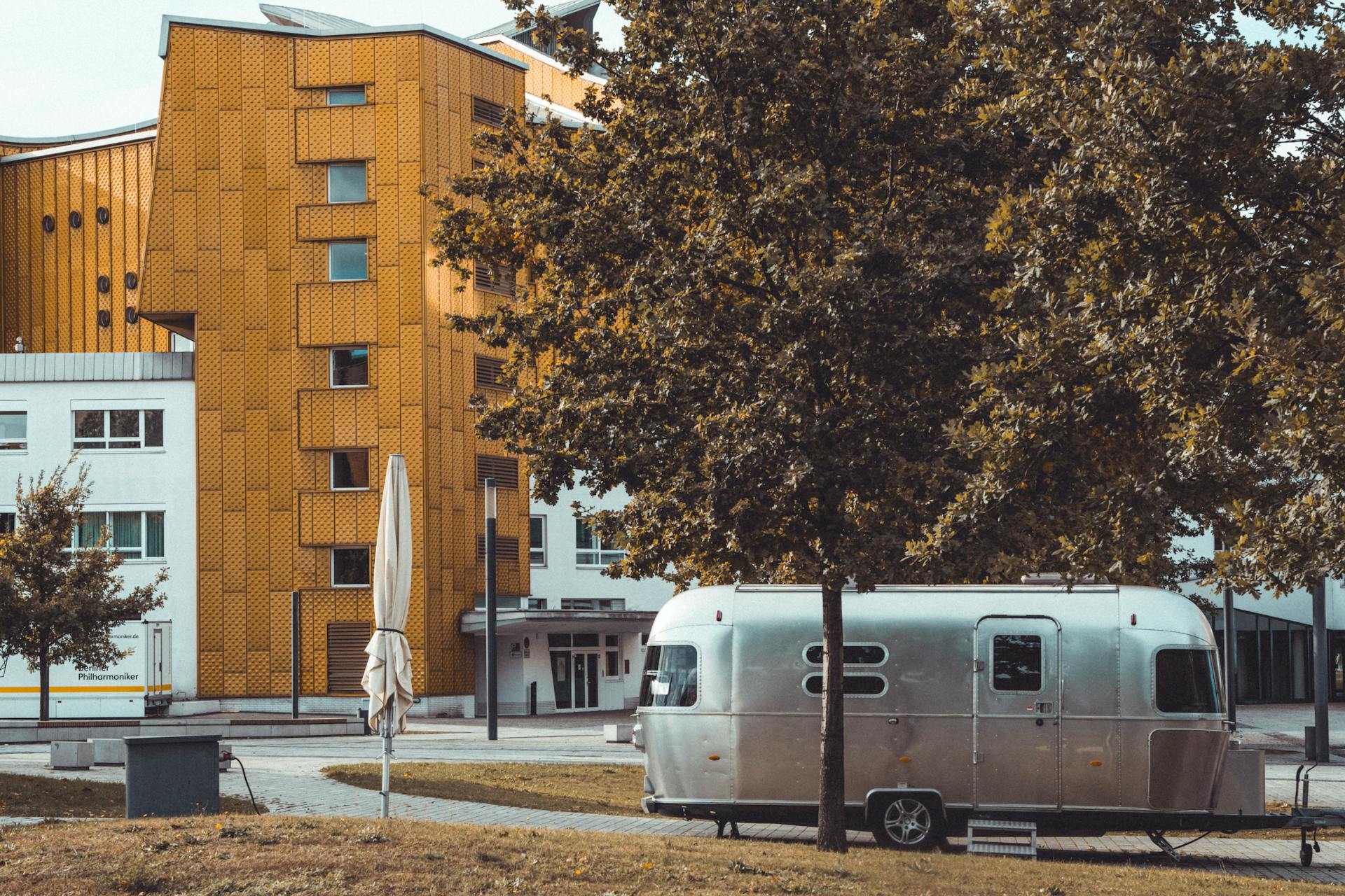 A sleek Airstream trailer parked near the iconic Berlin Philharmonic building.