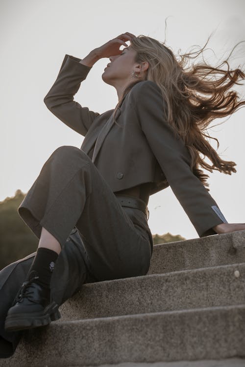 Blonde Woman in Elegant Black Cropped Blazer and Pants Sitting on Steps