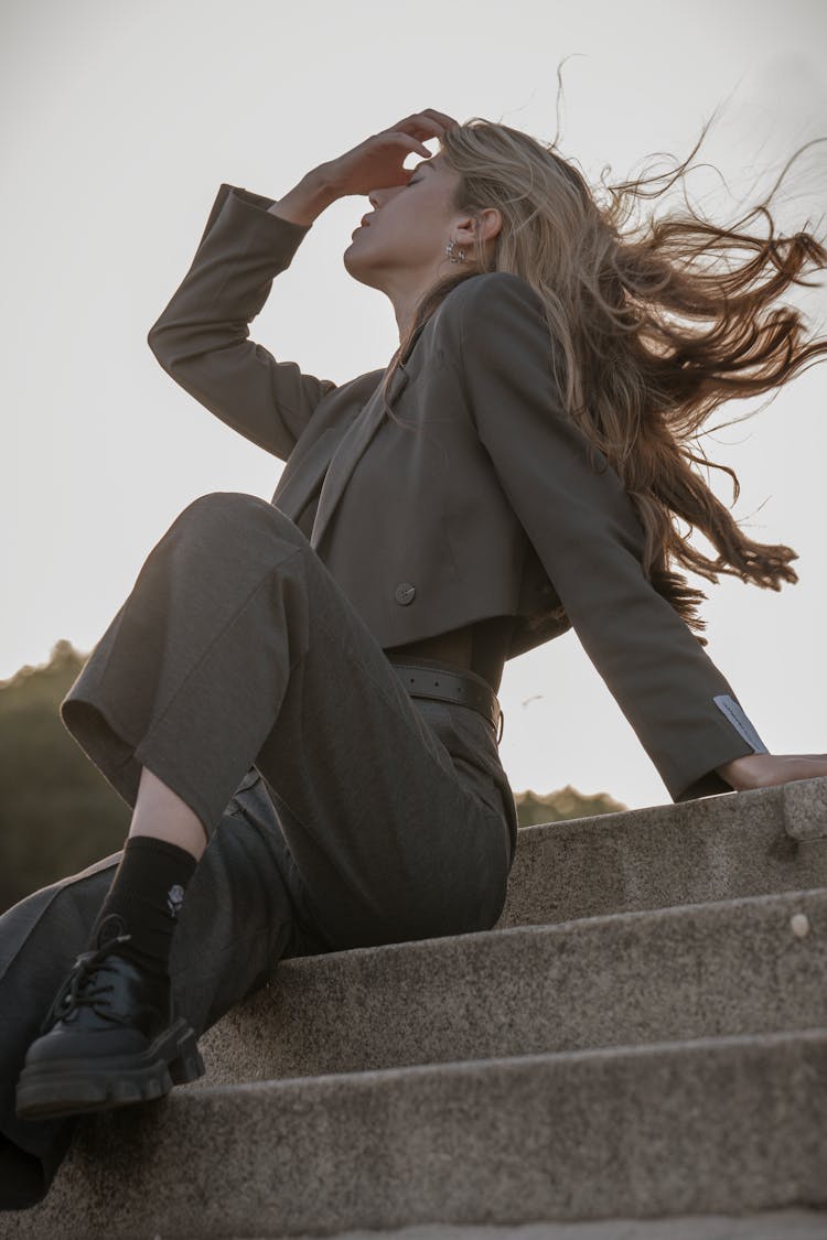 Blonde Woman In Elegant Black Cropped Blazer And Pants Sitting On Steps