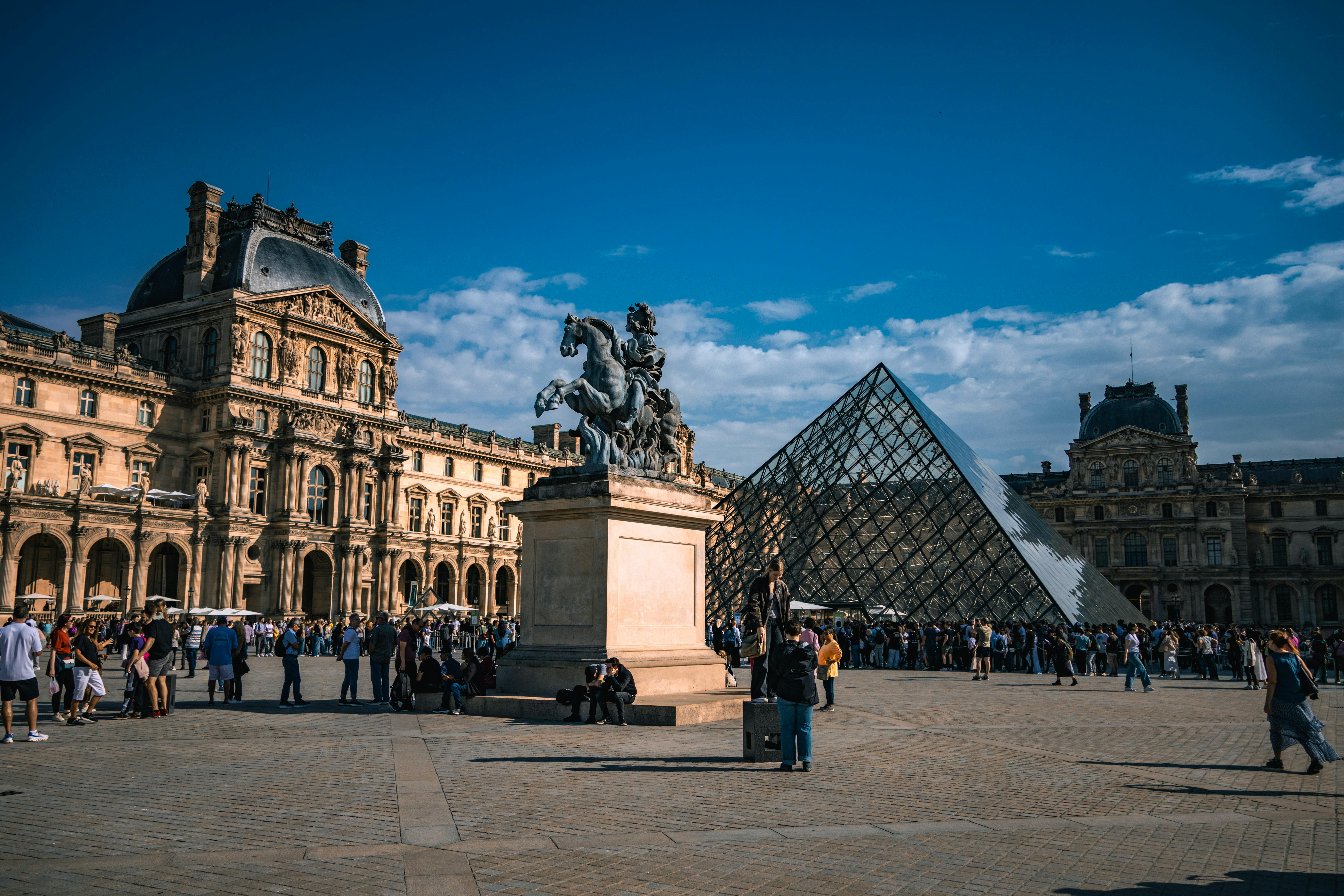 Stunning view of the Louvre Museum with the iconic glass pyramid and vibrant courtyard in Paris.