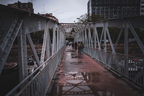 Free People walking on a wet metal bridge in a city after rain. Stock Photo