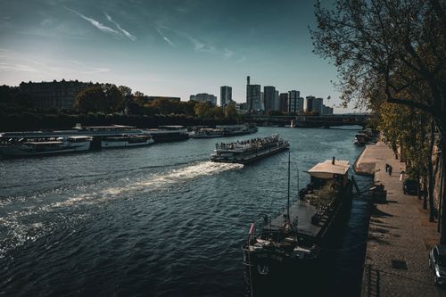 Free A busy river scene with boats and a modern city skyline on a sunny day. Stock Photo