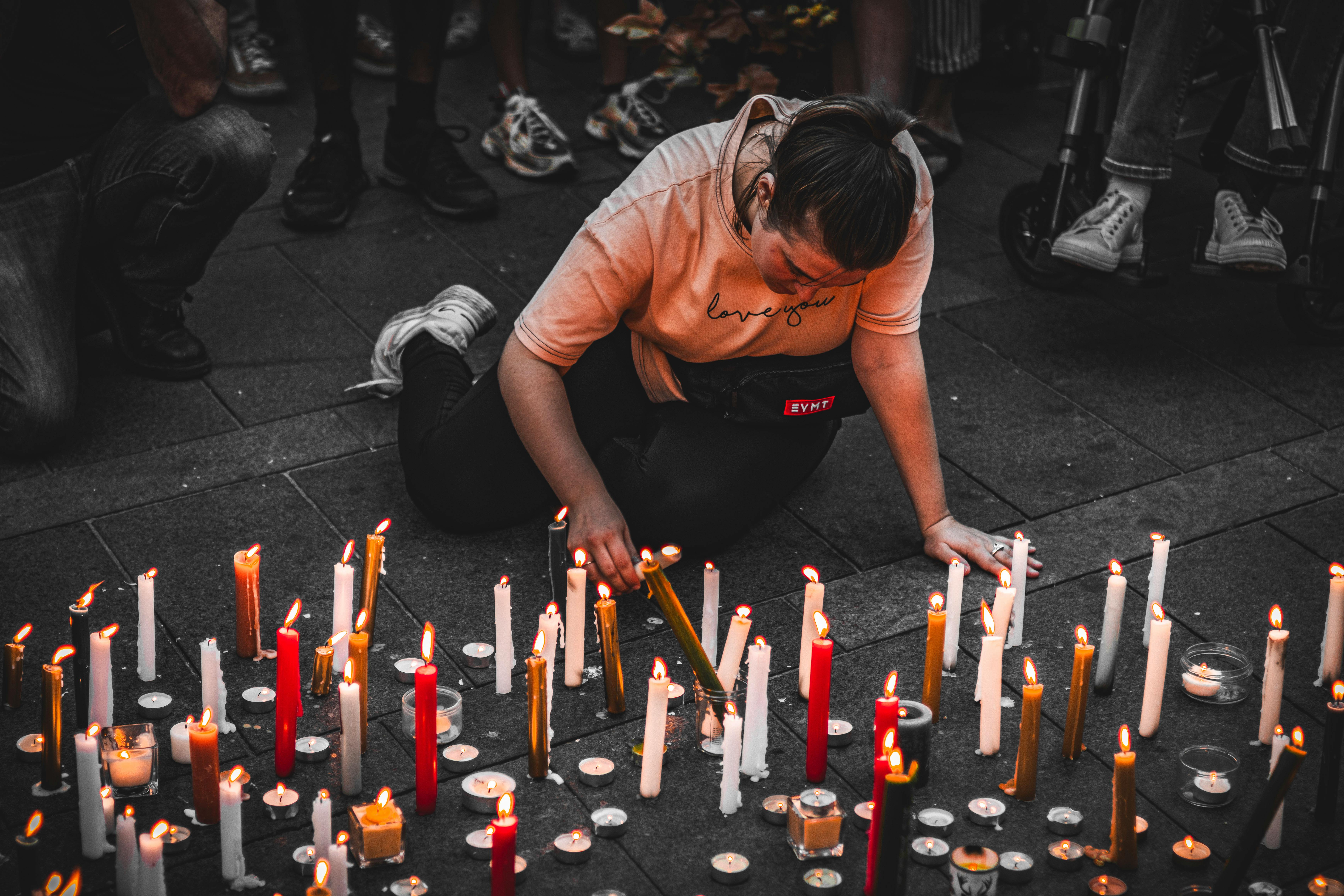 Woman Lighting Memorial Candles on the Sidewalk