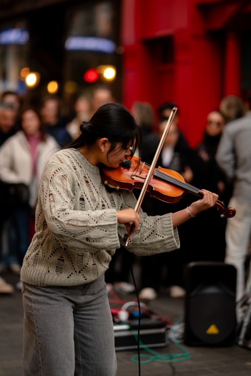 Free Female violinist performing on a busy street in London, captivating a crowd. Stock Photo