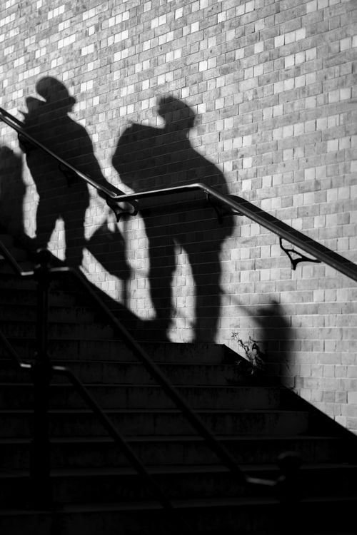 Free Silhouetted figures cast shadows on a brick wall in a London stairwell. Stock Photo