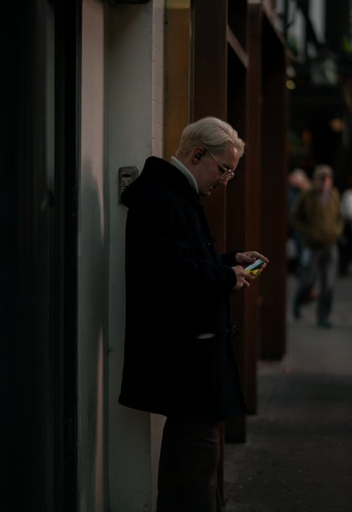 Man in Hooded Coat Looking at Smartphone