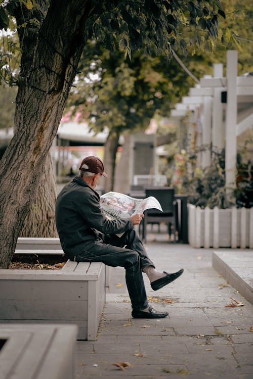 Elderly Man Reading Newspaper on a Street